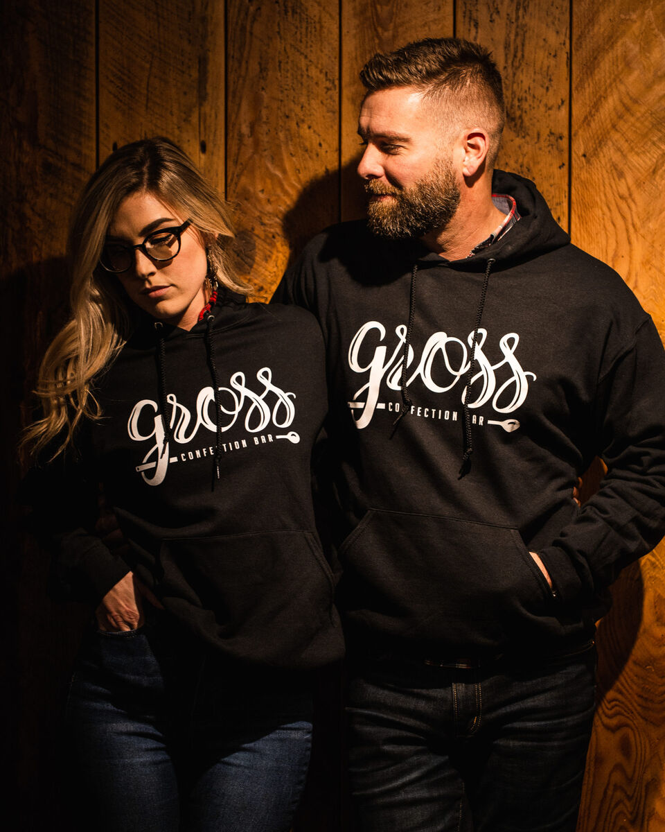 Two people wearing black Gross hoodies
